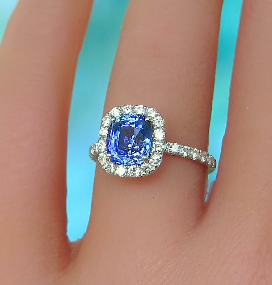 cushion cut sapphire with clear stones in halo design in silver white gold metal on the hand