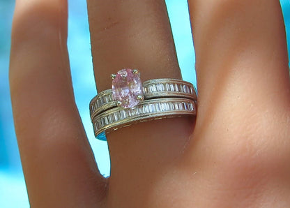 A close-up of a hand wearing a white gold double-band ring set with baguette diamonds and a central oval pink gemstone.