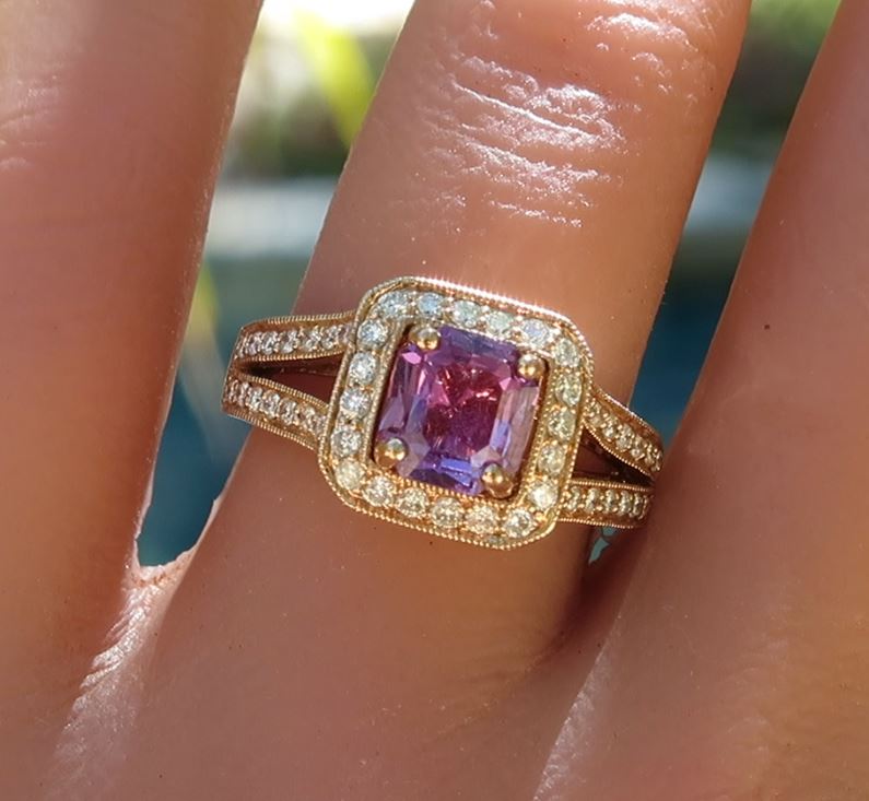 A rose gold ring with a square-cut purple sapphire gemstone and round diamonds, shown worn on a finger.