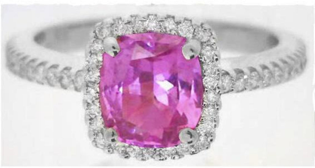 A silver-toned ring featuring a cushion-cut pink gemstone in a halo setting, with a pavé band adorned with small clear stones, shown against a plain white background.