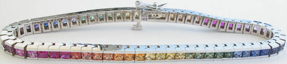 A white gold tennis bracelet featuring a continuous row of princess-cut rainbow-colored natural sapphire gemstones, displayed on a white background.