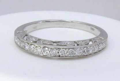 A white gold diamond band ring with a row of round-cut diamonds and an openwork pattern on the band, displayed on a white surface.
