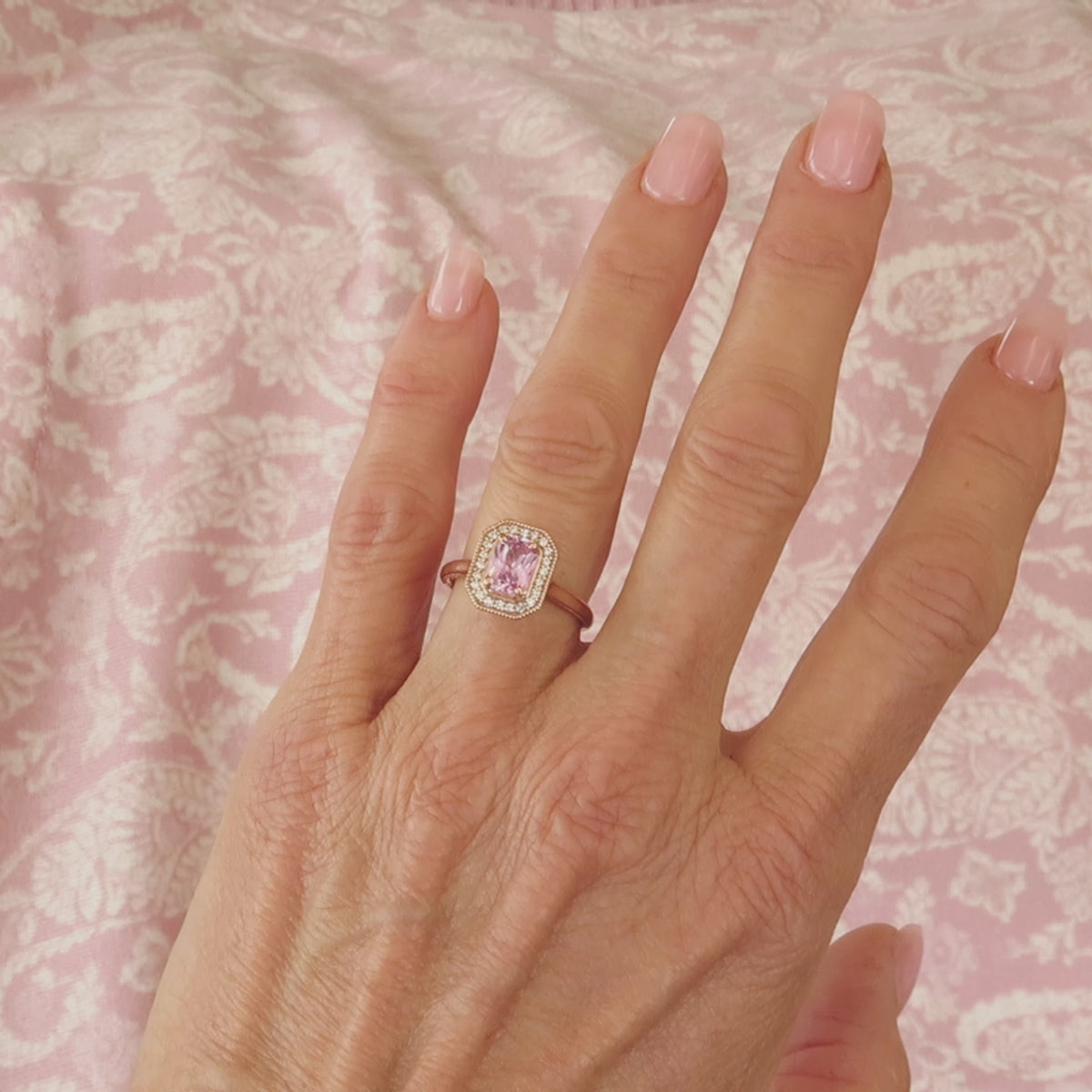 light pink radiant cut sapphire in a diamond halo vintage setting in rose gold on the finger