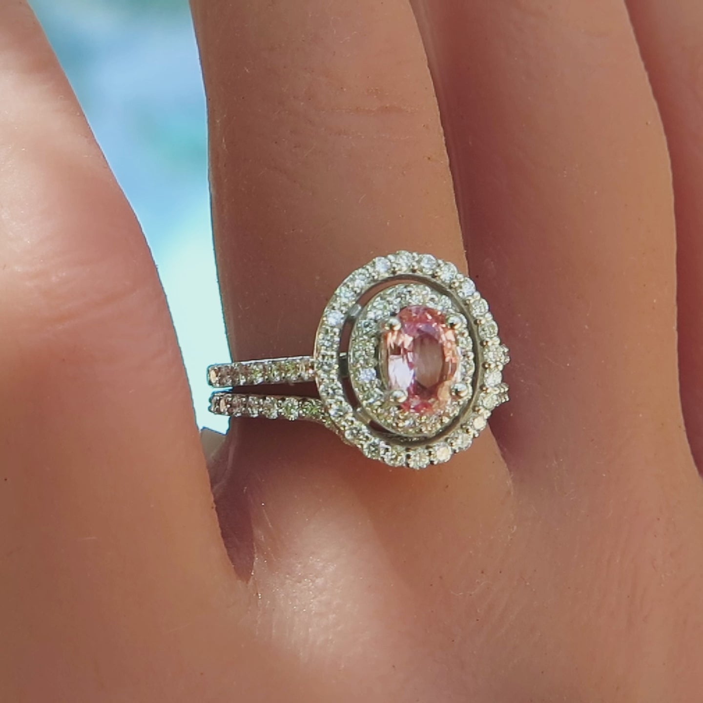 natural peach sapphire and double diamond halo engagement ring and band on the finger