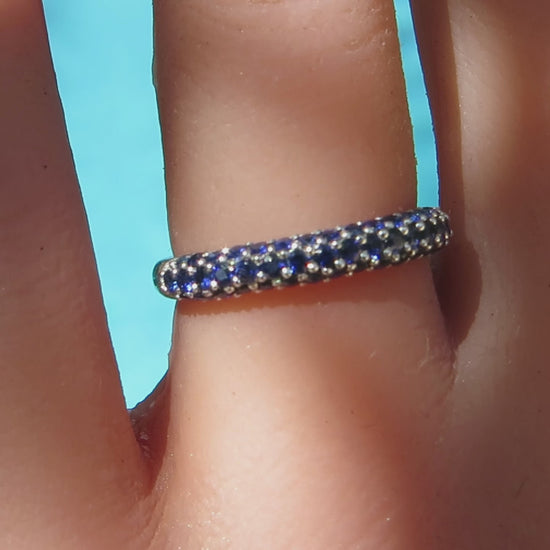 bright blue round sapphires set in 3 rows in a pave style anniversary ring in white gold on the finger