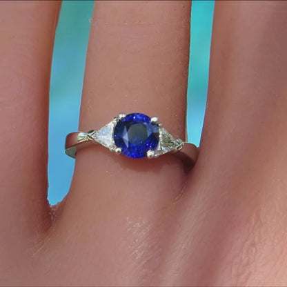 three stone sapphire and clear diamond trillion cut ring in 14k white gold on ladies hand
