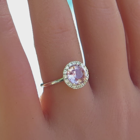 simple diamond halo ring with round light pink sapphire shown on the finger