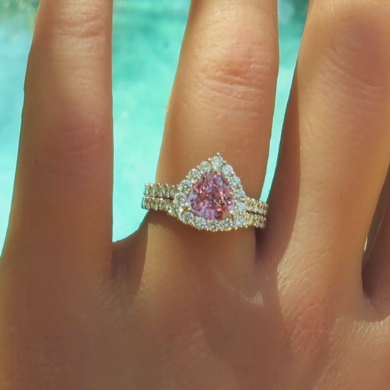 engagement ring and band with trillion cut light pink sapphire in a diamond halo setting in white metal platinum on the finger