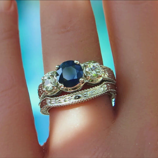 round sapphire ring with matching band done in a white metal 18k gold with engraved detail on a ladies' hand