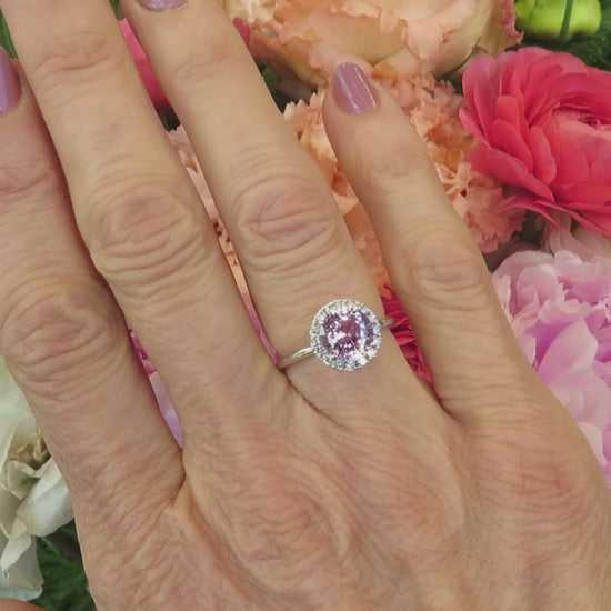 pale pink sapphire diamond halo ring with skinny band in white gold on the hand with a pastel floral background