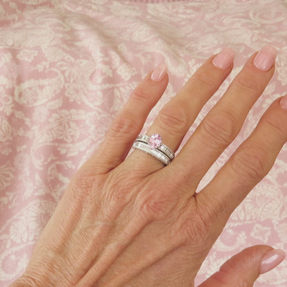 oval pink sapphire diamond wedding set in 18k white gold on the hand with a pink background