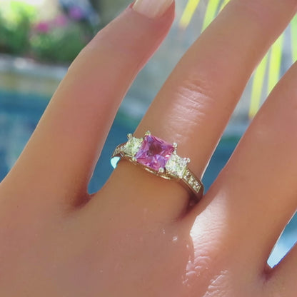 princess cut pink sapphire and princess cut diamond ring with channel set princess cut white sapphires in 14k white gold setting on the hand