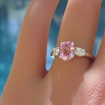 three stone oval pink sapphire and round diamond ring in white gold on the finger