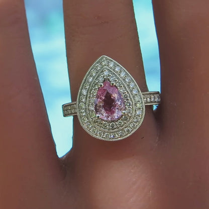 close up of statement making diamond halo pear shape pink sapphire ring on the finger