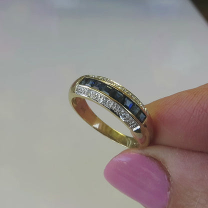 simple channel set sapphire band with tiny diamond accents in yellow gold on the finger