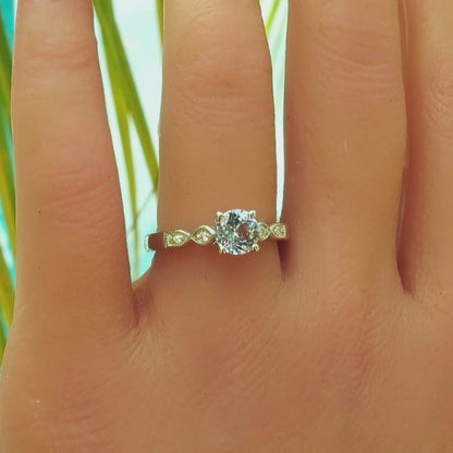 delicate pastel blue sapphire ring with small round diamonds and milgrain detail on the hand