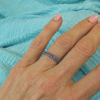 anniversary band with three rows of pave set blue sapphires shown on the hand