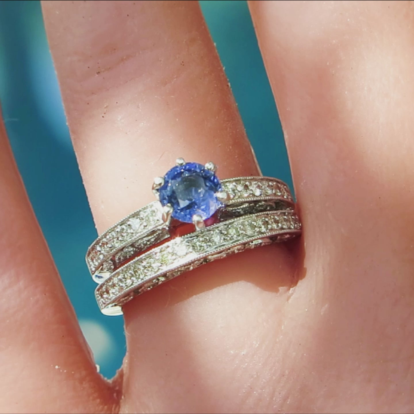 antique style sapphire engagement ring and band with round cornflower blue stone in 14k white gold on the finger