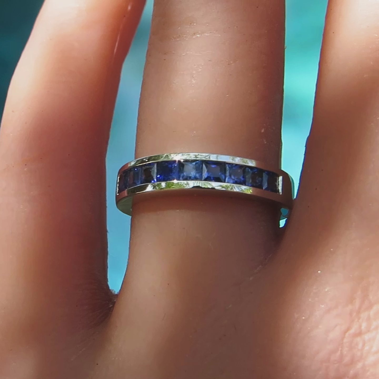 all sapphire anniversary ring with princess cut stones on the finger