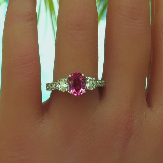 oval pink sapphire and oval diamond ring with diamonds in the band with milgrain edging shown on the hand