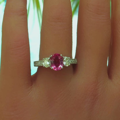 oval pink sapphire and oval diamond ring with diamonds in the band with milgrain edging shown on the hand