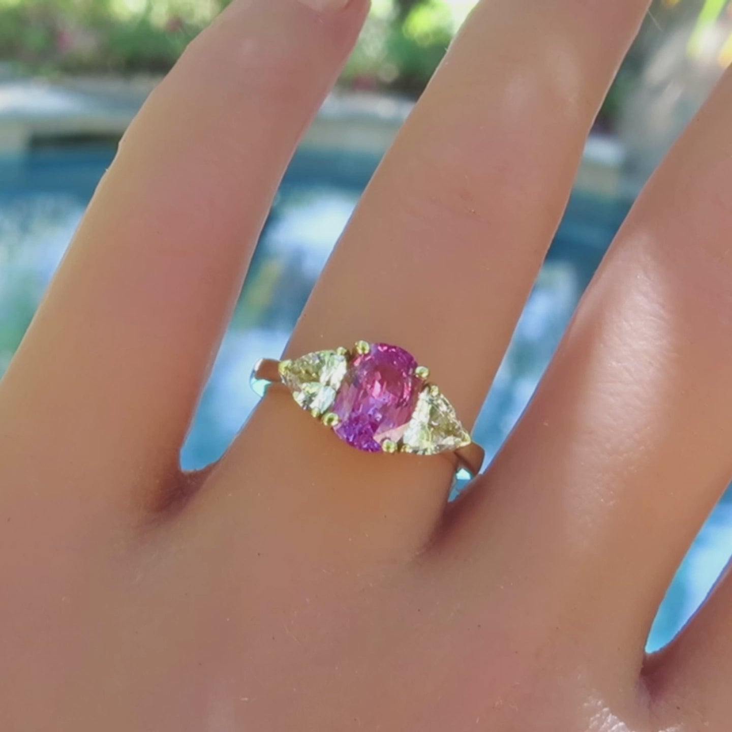 unheated hot pink sapphire 3 stone ring with trillion white sapphires in yellow gold on the finger