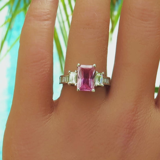 natural radiant cut pink sapphire with large and small baguette diamonds in a white gold setting on the finger