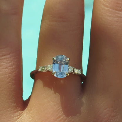 Pastel oval sapphire flanked by round and baguette clear diamonds in a skinny band on the finger