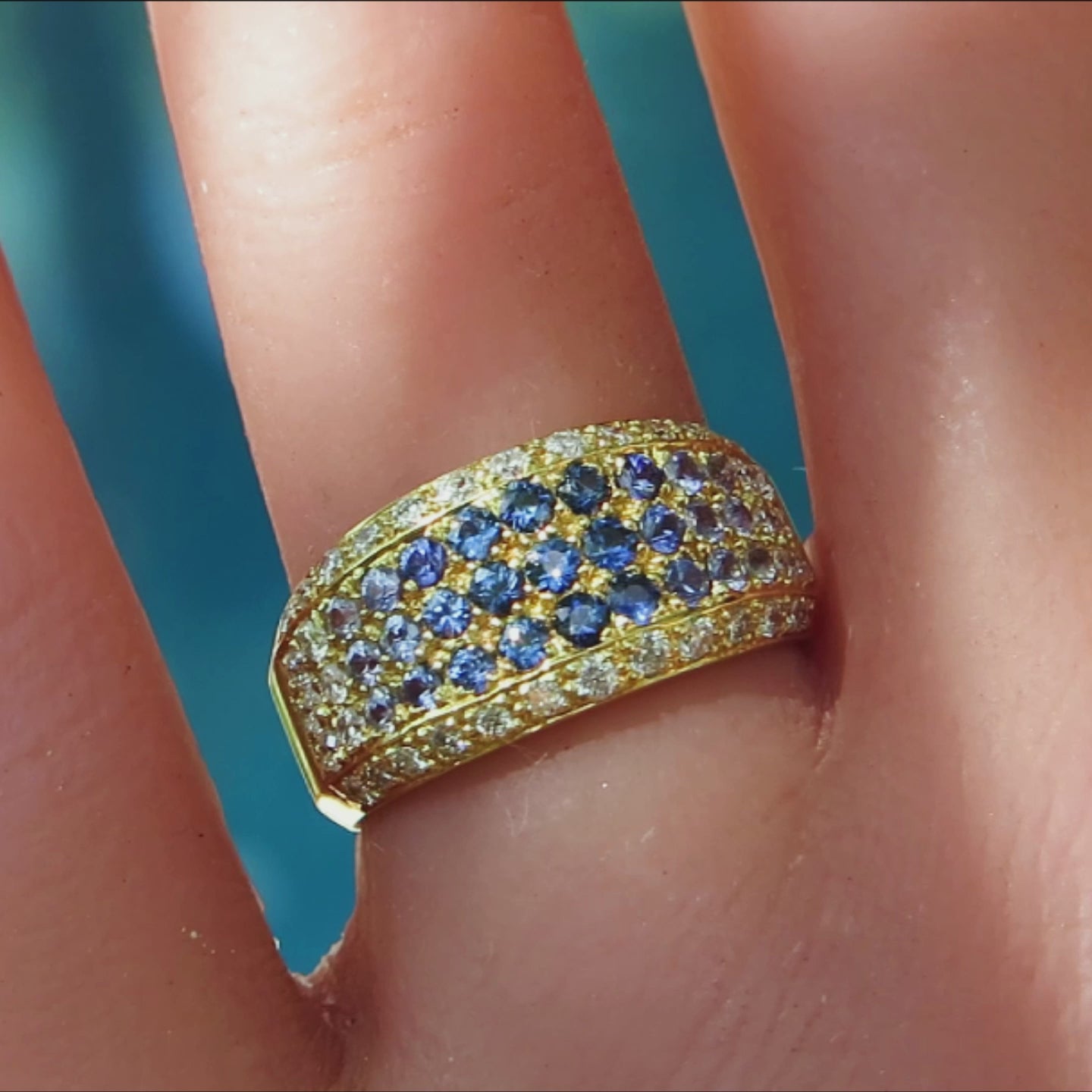 shades of blue sapphire pave ring with diamonds in 18k yellow gold on the finger