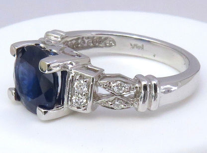 A white gold ring featuring a 8mm round cut dark blue sapphire center stone and small clear accent diamonds, shown on a plain white background.