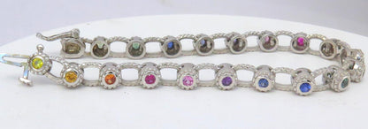 A white gold tennis bracelet with multiple round-cut rainbow sapphires in various colors including pink, blue, yellow, and green, displayed on a white background.