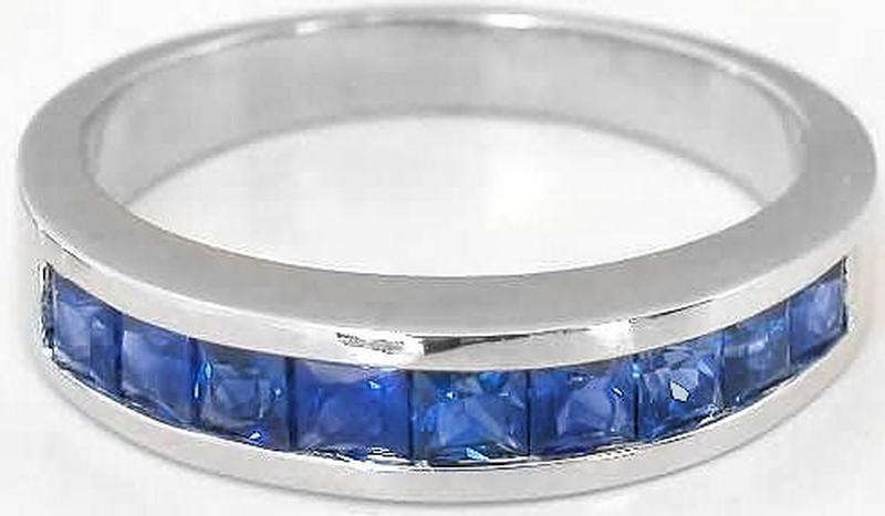 A silver band ring featuring a row of square-cut blue gemstones in a channel setting, shown against a plain white background.