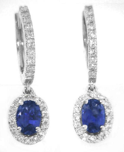 A pair of white gold huggie hoop earrings with pavé-set diamond and oval blue sapphire drops, shown on a plain white background.