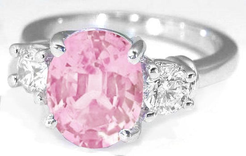 Natural Pink Sapphire in an Oval Cut and Round Cut Diamond Three Stone Engagement Ring in 14k white gold