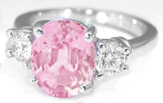 Natural Pink Sapphire in an Oval Cut and Round Cut Diamond Three Stone Engagement Ring in 14k white gold